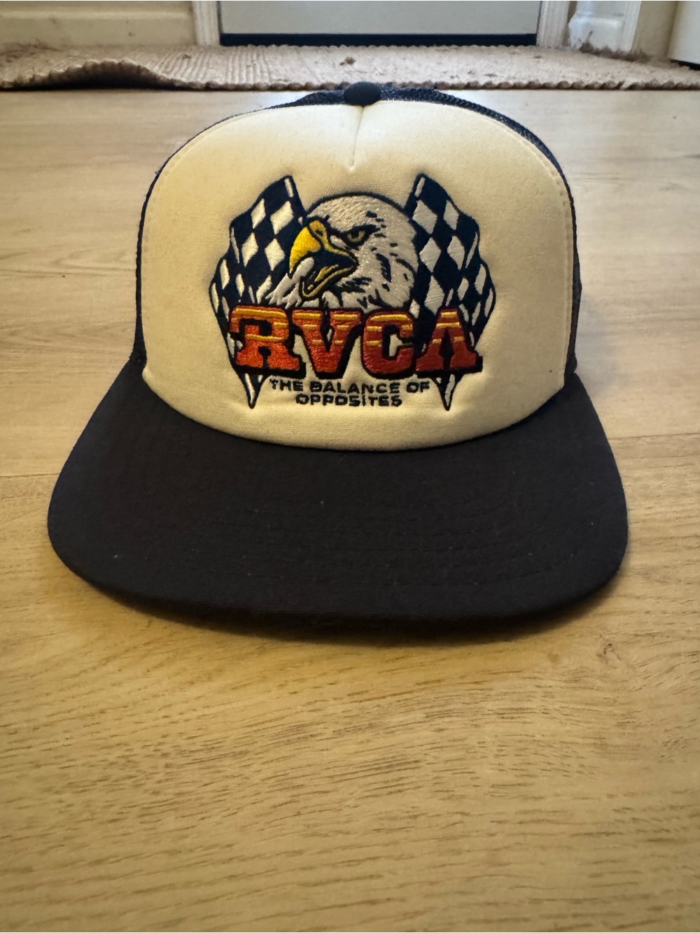 RVCA Two-Tone Eagle Patch Trucker Hat in Black & Cream with Orange Logo.